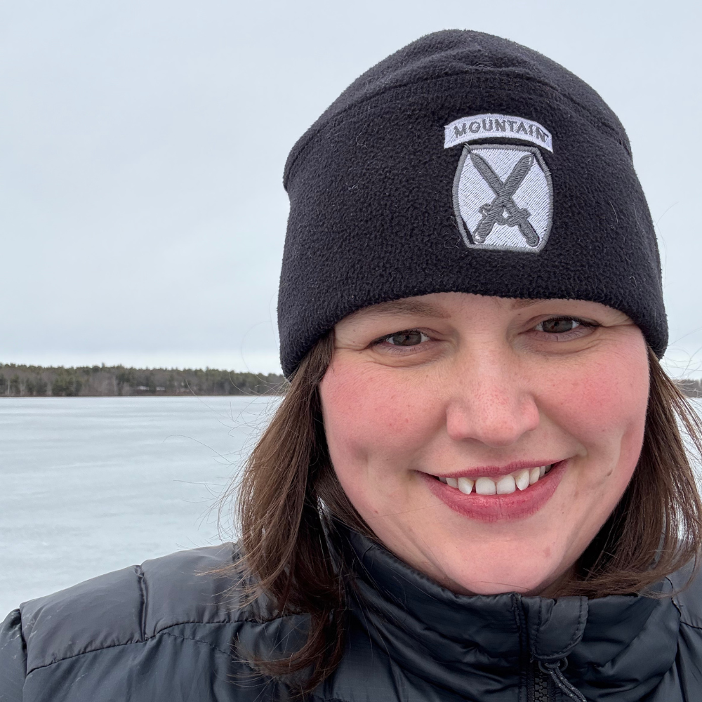 Woman standing on iced over lake smiling.