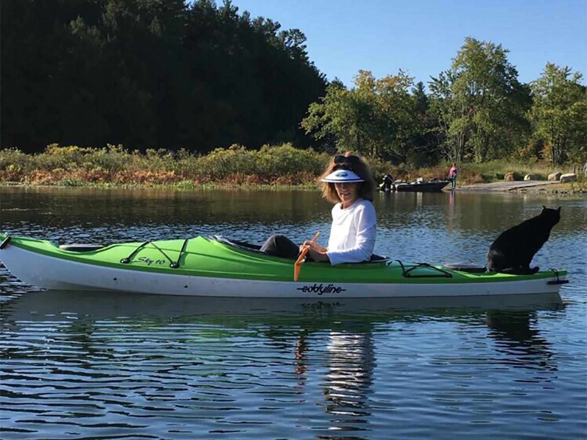cat sitting on kayak as they paddle across the lake