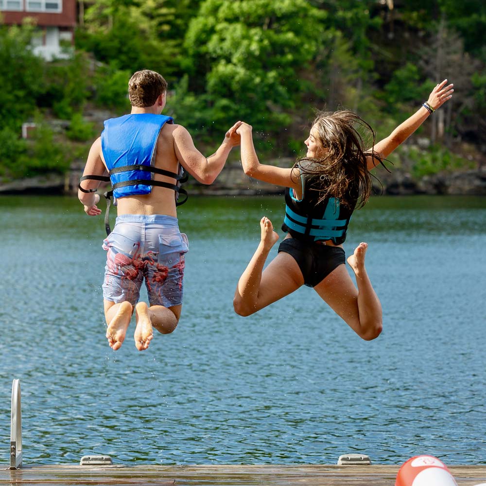 two people jumping in the lake