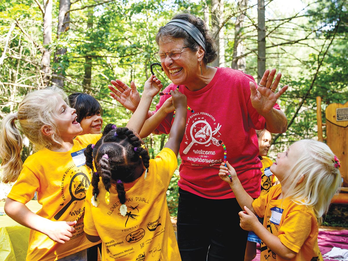 volunteer surrounded by giddy Nature camp kids