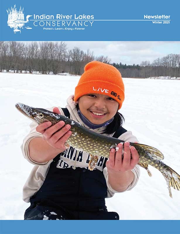 A young boy holding a pike caught during ice fishing