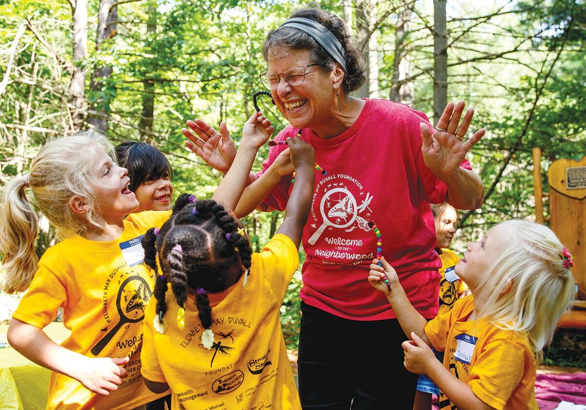 volunteer surrounded by giddy Nature camp kids